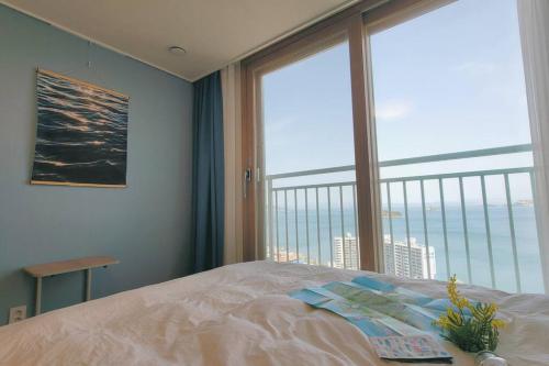 a bedroom with a bed and a large window at Ocean view Full Option 4Bed 3Room APT in Geoje 