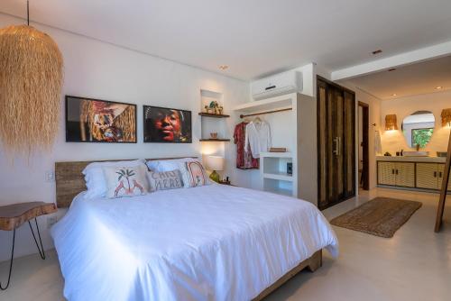 Un dormitorio con una gran cama blanca y una cocina. en Nossa Villa Caraíva, en Caraíva