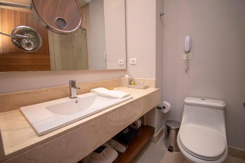 a bathroom with a sink and a toilet and a mirror at DoubleTree by Hilton Bogota Parque 93 in Bogotá