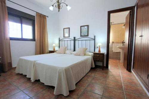 コニル・デ・ラ・フロンテーラにあるVillas Rocío ConiLのベッドルーム(大型ベッド1台付)、バスルームが備わります。