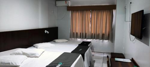 Habitación con 2 camas y TV. en Hotel LF By Feliciano, en Barracão