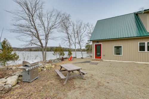 a picnic table next to a building with a stove at Lakefront Bucksport Home with Fire Pit and Gas Grill! in Bucksport