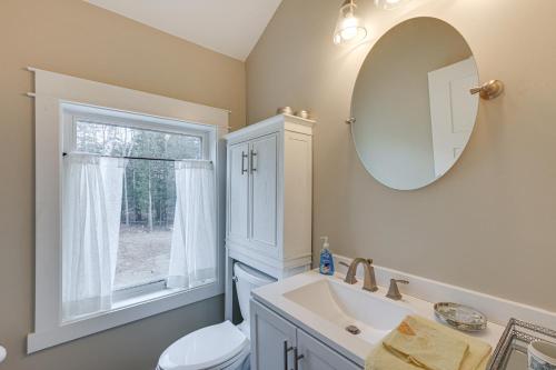 a bathroom with a sink and a toilet and a mirror at Lakefront Bucksport Home with Fire Pit and Gas Grill! in Bucksport