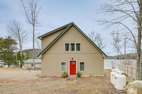 a house with a red door in a yard at Lakefront Bucksport Home with Fire Pit and Gas Grill! in Bucksport