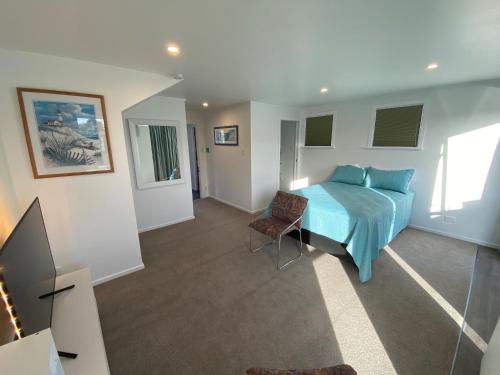 um quarto com uma cama azul e uma cadeira em Birch Court - Tui em Whanganui