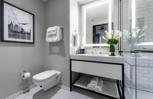 a white bathroom with a toilet and a sink at Hanza Tower BokiejHotels - studio in Szczecin