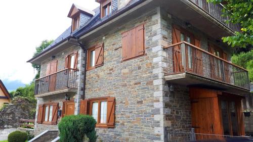 a brick building with wooden doors and a balcony at Charming Chalet in Viella, Mountain View in Vielha