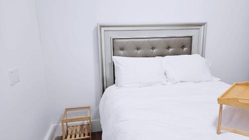 uma cama branca com uma cabeceira de cama prateada e almofadas brancas em 3bed 1 bath suite - Surrey Fleetwood em Surrey