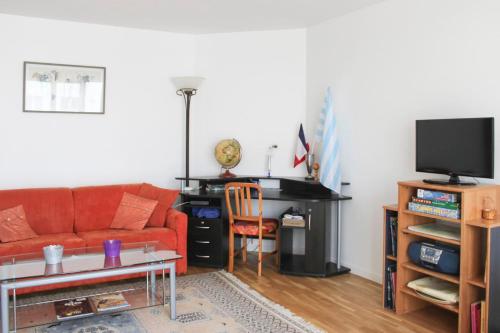 een woonkamer met een rode bank en een piano bij Bright and quiet apartment with unobstructed view in Boulogne-Billancourt