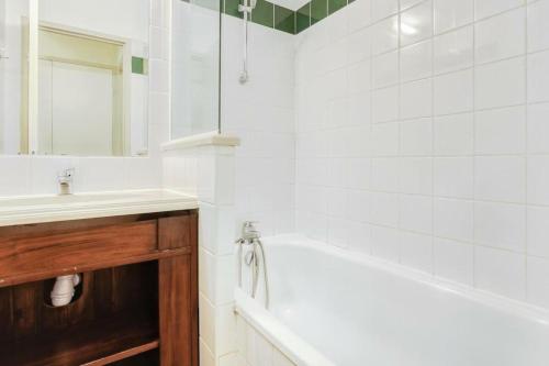 La salle de bains blanche est pourvue d'une baignoire et d'un lavabo. dans l'établissement Résidence Les Belles Rives - maeva Home - Appartement 2 pièces 5 personnes - 334, à Argentat