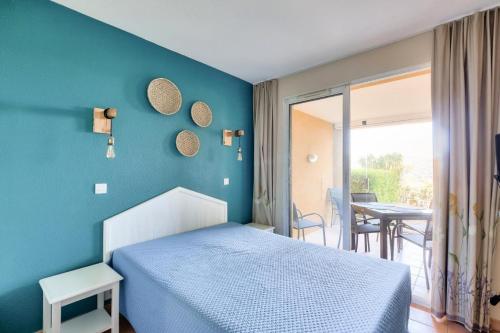 une chambre avec un lit et un mur bleu dans l'établissement Résidence le Hameau des Issambres - maeva Home - Appartement 3 Pièces 7 Personnes - Prestige MAE-4534, aux Issambres