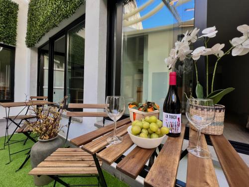 un tavolo in legno con un cesto di frutta e bicchieri da vino di Sorolla Urban Suites a Valencia