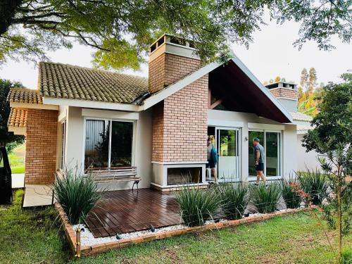two people standing on a deck in front of a house at Casa de Campo - Rancho dos Lagos in Cascavel