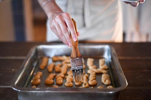 a person holding a wooden spatula over a pan of donuts at The Romanos, a Luxury Collection Resort, Costa Navarino in Romanós