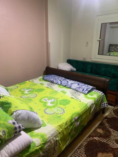 een slaapkamer met een bed met een groen dekbed bij Bienvenidodepartamento in Caïro