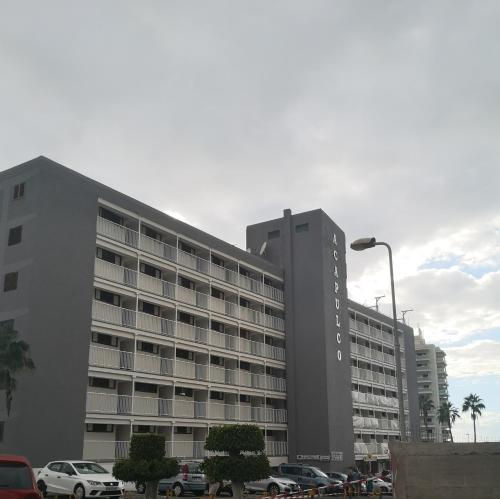 un gran edificio con coches estacionados en un estacionamiento en Lovely apartment in Costa Adeje, en Playa Fañabe