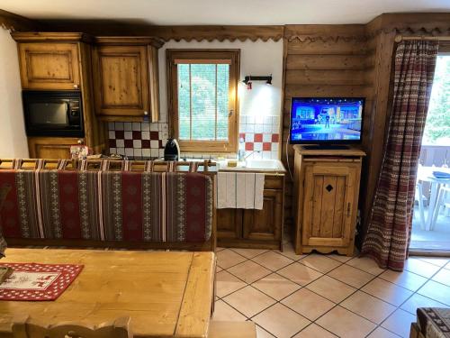 une cuisine avec des placards en bois et une télévision sur un comptoir dans l'établissement Résidence La Ginabelle - maeva Home - Appartement 3 pièces 6 personnes - Sélection MAE-2964, à Chamonix-Mont-Blanc