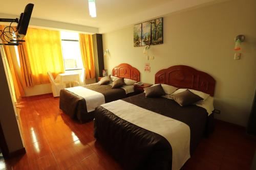 una camera d'albergo con due letti e una finestra di Hotel Frontera a Tacna