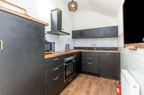 een keuken met zwarte kasten en een houten vloer bij Leinster Suite, 7 Henrietta Street, Dublin 1 in Dublin