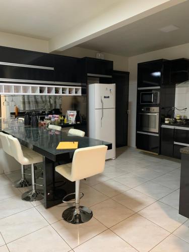 uma cozinha com armários pretos, uma mesa preta e cadeiras em Casa espaçosa e aconchegante em Luis Eduardo Magalhaes