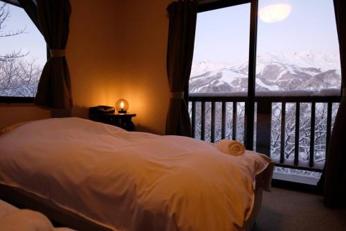 a bedroom with a bed and a window with mountains at WAKURABA- Chalet with the best views in Hakuba! in Hakuba