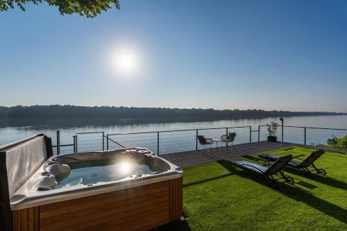 a hot tub on a deck next to a body of water at Duna Rév Apartman in Bogyiszló