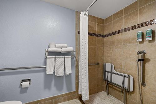 a bathroom with a shower and towels on a wall at Best Western Moreno Hotel & Suites in Moreno Valley