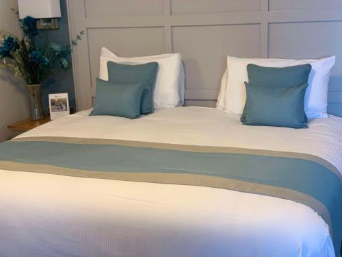 a large bed with blue and white pillows on it at Best Western Manor Hotel in Gravesend