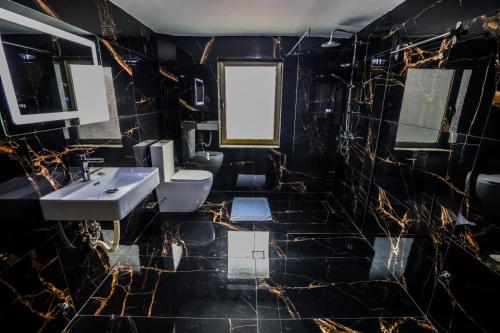 ein Badezimmer mit schwarzen Marmorwänden, einem Waschbecken und 2 WCs in der Unterkunft VILA ALIZEE Hotel in Tirana