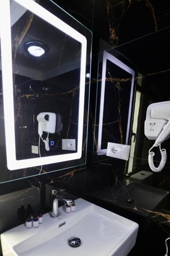 a bathroom with a white sink and two mirrors at VILA ALIZEE Hotel in Tirana