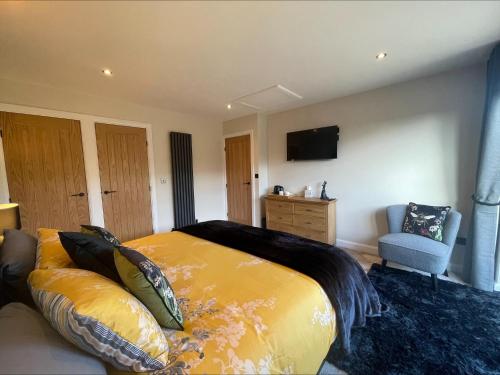 een slaapkamer met een groot bed en een bank bij Bumblebee Barn, Luxury contemporary holiday home in Perranporth