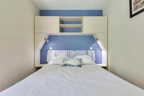 - un lit blanc avec une tête de lit bleue dans l'établissement Résidence Lacanau Les Pins - maeva Home - Appartement 2 pièces 5 personnes - Prestige MAE-4844, à Lacanau