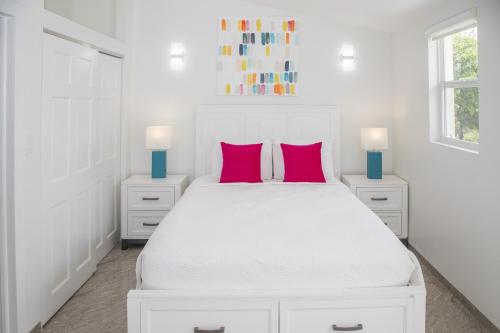 a white bedroom with a white bed with two pink pillows at 247C South Finger in Jolly Harbour