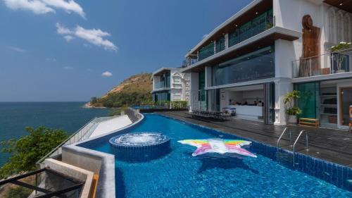 a house with a swimming pool next to the ocean at Villa Thousand Cliffs in Nai Harn Beach