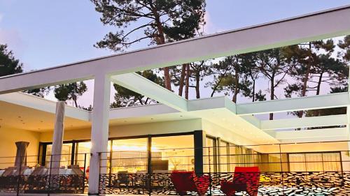 un grand bâtiment avec des fenêtres en verre et des chaises rouges dans l'établissement Villa CALIFORNIA Piscine chauffée 14x4m Moulleau Abatilles 10 pers, à Arcachon