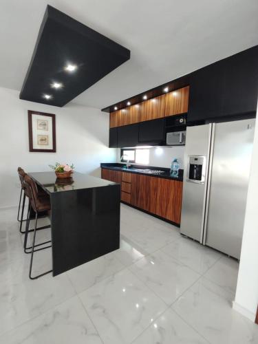 a kitchen with a refrigerator and a table with chairs at Pent-house a media cuadra del malecón, Hookipa Tower! in Mazatlán