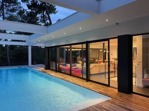 une piscine dans une maison avec un salon dans l'établissement Villa CALIFORNIA Piscine chauffée 14x4m Moulleau Abatilles 10 pers, à Arcachon