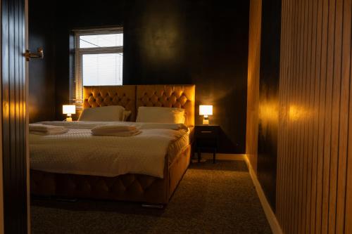 a bedroom with a bed with two lamps and a window at The Orange County in Stoke on Trent