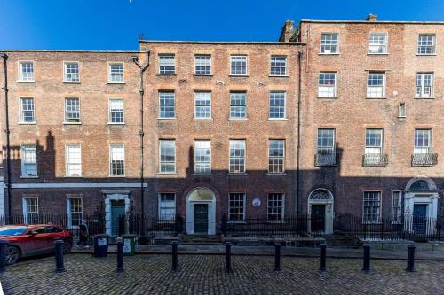 ein großes Backsteingebäude mit einem roten Auto vor dem Haus in der Unterkunft Munster Suite, 7 Henrietta Street, Dublin 1 in Dublin