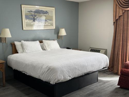 a bedroom with a large bed with white sheets at Days Inn by Wyndham Medford in Medford