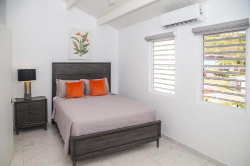 a bedroom with a bed with orange pillows and a window at 101G Jolly Harbour, Garden View in Jolly Harbour