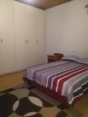 a bedroom with a bed and white cabinets and a rug at Old style Room @48 in Gqeberha
