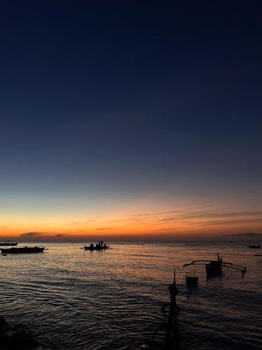 a group of boats in the water at sunset at Gloria's Beach House in Oslob