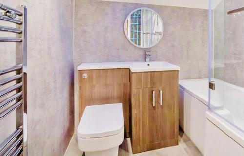 a bathroom with a toilet and a sink and a mirror at Luxury Spacious Apartment in Cardiff