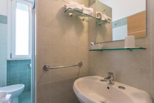y baño con lavabo y espejo. en Hotel Dafne, en Punta Marina
