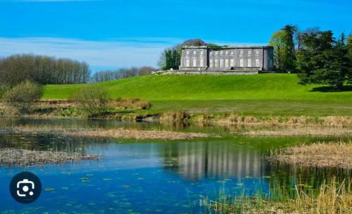 a house on top of a hill next to a pond at Country Hideaway in Limerick