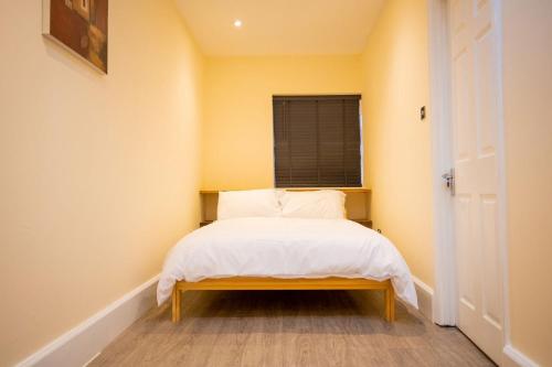 a small bedroom with a bed with white sheets and a window at GOLDEN HAVEN in Reading