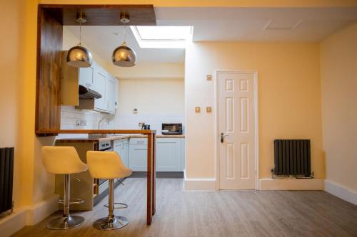 a kitchen with yellow walls and a counter and chairs at GOLDEN HAVEN in Reading