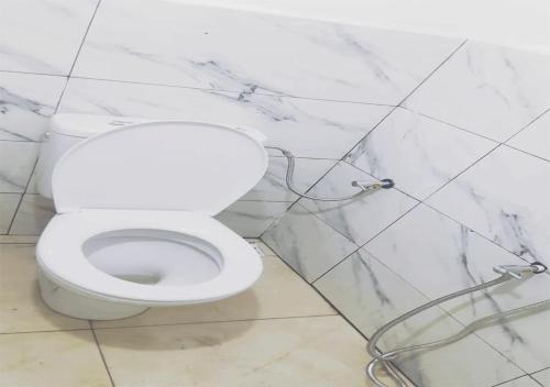 a white toilet in a bathroom with marble walls at A room in a shared house for surfers2 in Safi