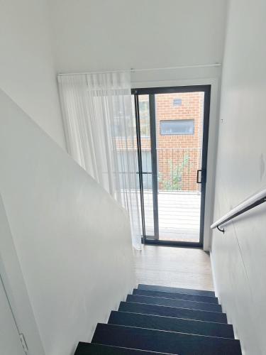 a staircase with a blue carpet and a glass door at Inn Central Townhouse at Canberra in Canberra
